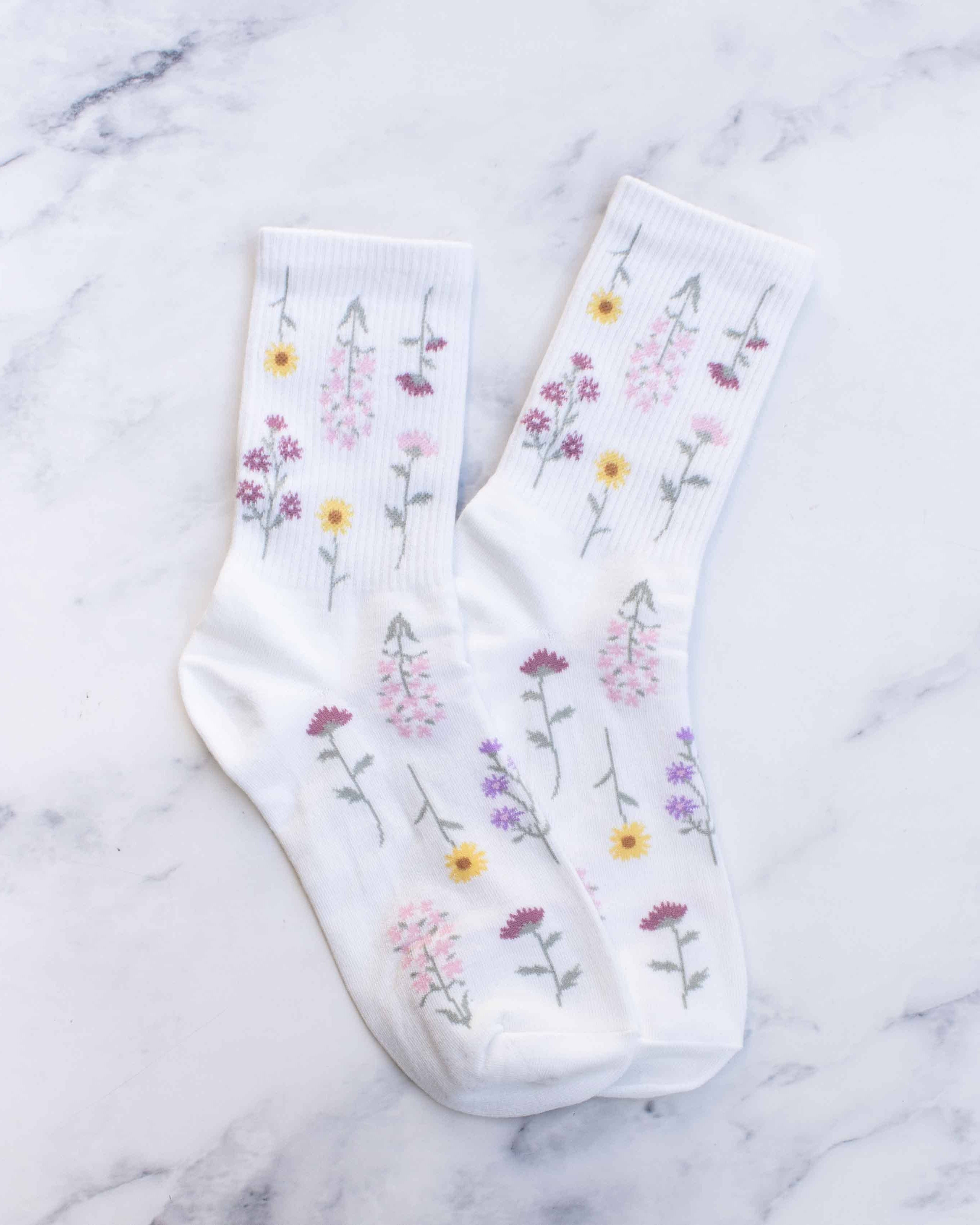 White socks with flower stem designs on a marble surface