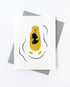 Greeting card with a yellow otter and black silhouette  of a baby otter on its chest on a white background