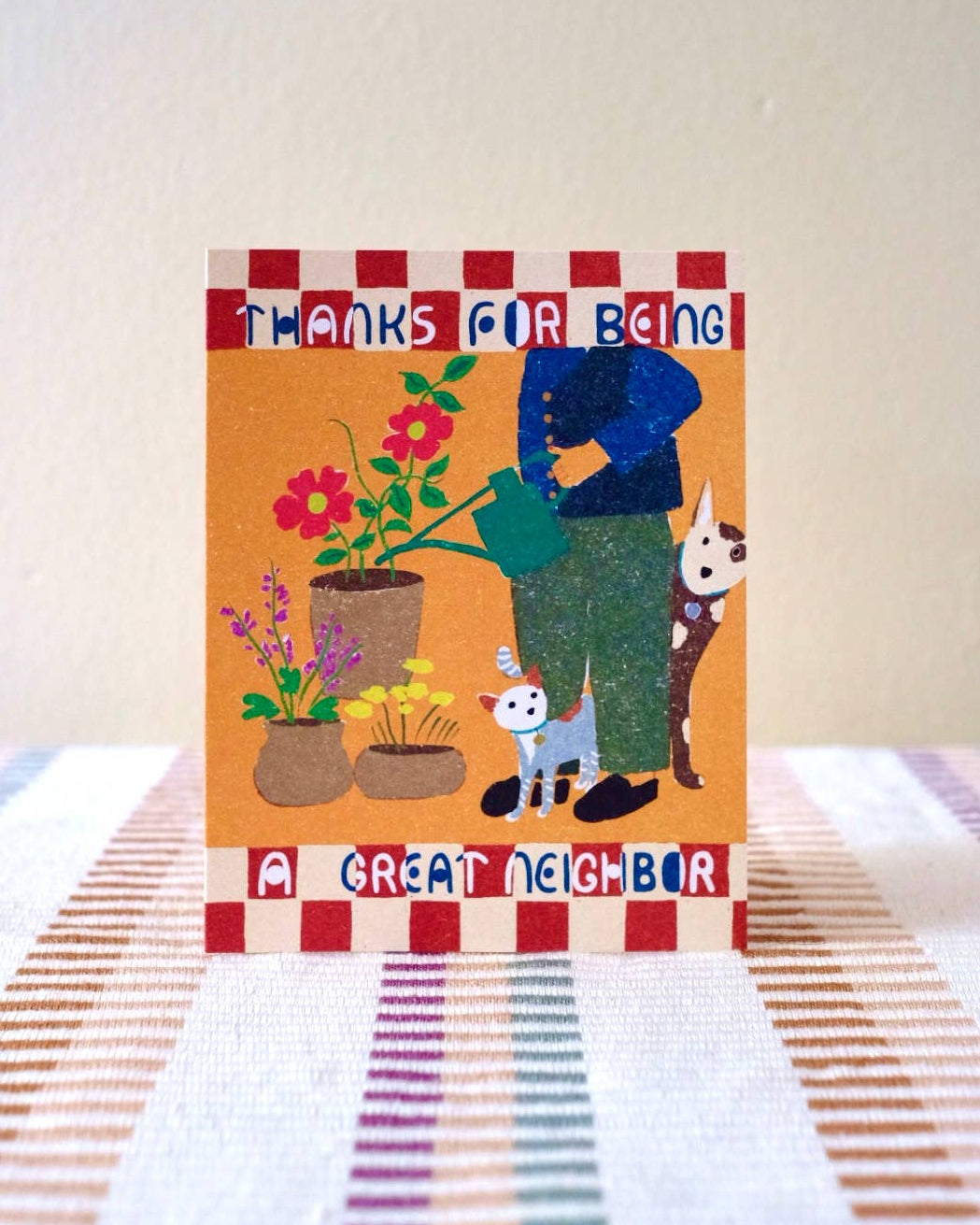 Card with illustration of a person watering plants, dog, and cat with text &